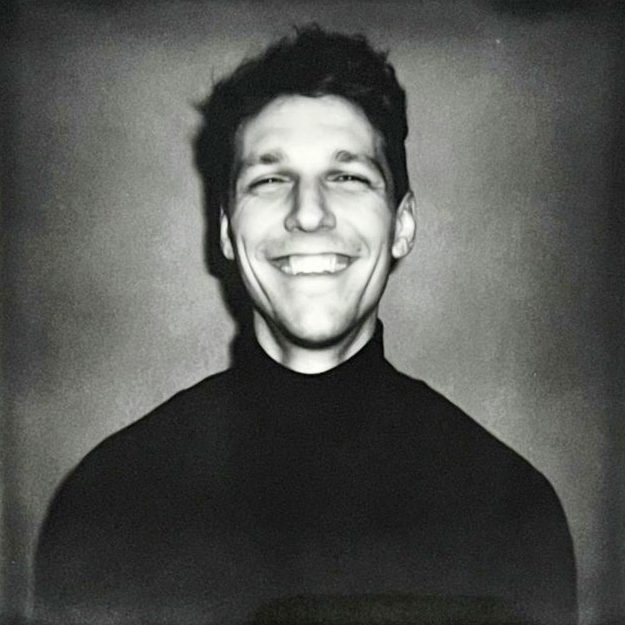 A black and white Polaroid Portrait of Robin Kater, looking into the camera, smiling. 